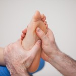 Podiatrist practicing reflexology on the foot of woman in a room